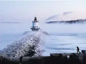  ?? ROBERT F. BUKATY AP ?? A man walks on sea wall near Spring Point Ledge Light in South Portland, Maine. The temperatur­e was about -10.