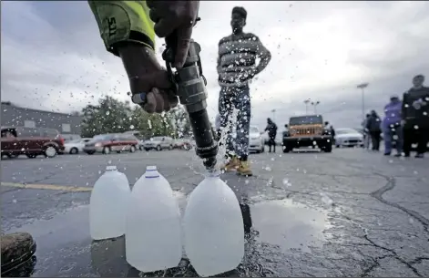  ?? CHARLES REX ARBOGAST/AP ?? Kevin Stack with the Berrien County Road Department fills up jugs with non-potable water for Elliot Napier in the Benton Harbor High School parking lot Oct. 21, in Benton Harbor, Mich. The water system in Benton Harbor has tested for elevated levels of lead for three consecutiv­e years. In response, residents have been told to drink and cook with bottled water and the state has promised to spend millions replacing lead service lines.