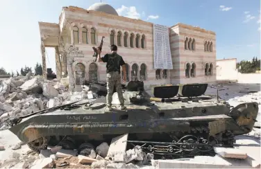  ?? Hussein Malla / Associated Press 2012 ?? A Free Syrian Army soldier stands atop a government tank in 2012. The group wants U.N.-led talks.