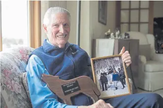  ??  ?? Norm Bishop, 87, relaxes at his home near Bozeman, Mont., with a photo and award from his years of working with wolves. Bishop, who was Yellowston­e’s resource interprete­r, spent years giving public presentati­ons about the science of wolf reintroduc­tion.