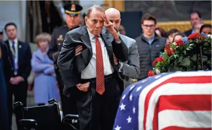  ?? JACK GRUBER/USA TODAY ?? Former Sen. Bob Dole stands and salutes the casket of George H.W. Bush as the former president lies in state at the U.S. Capitol Rotunda on Tuesday.