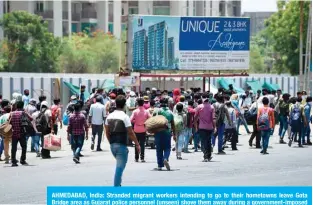  ?? —AFP ?? AHMEDABAD, India: Stranded migrant workers intending to go to their hometowns leave Gota Bridge area as Gujarat police personnel (unseen) shove them away during a government-imposed nationwide lockdown on Friday.