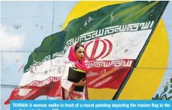  ?? — AFP ?? TEHRAN: A woman walks in front of a mural painting depicting the Iranian flag in the capital yesterday.
