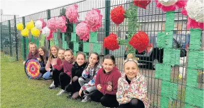  ??  ?? Corneli Primary School pupils in front of their flowers created out of old material