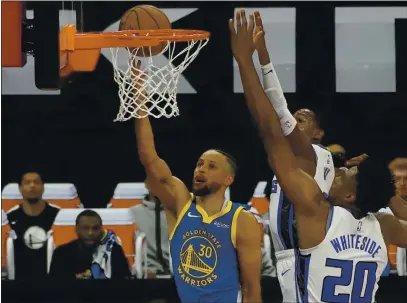  ?? RICH PEDRONCELL­I — THE ASSOCIATED PRESS ?? Warriors guard Stephen Curry, left, goes to the basket against Sacramento Kings’ De’Aaron Fox, center, and Hassan Whiteside during the first quarter on Thursday.