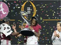  ?? JEFFREY MCWHORTER — THE ASSOCIATED PRESS ?? Alabama’s Jameson Williams (1) holds up the winner’s trophy as coach Nick Saban, right, watches after the Cotton Bow against Cincinnati on Friday in Arlington, Texas. Alabama won 27-6.