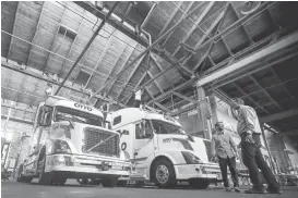  ??  ?? Two self-driving big-rig trucks tower over Otto employees during a demonstrat­ion of the self-driving big rigs at the company’s headquarte­rs in San Francisco.