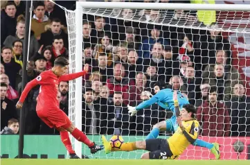  ?? - AFP photo ?? Liverpool’s Brazilian midfielder Roberto Firmino (L) shoots past Arsenal’s Czech goalkeeper Petr Cech to score the opening goal of the English Premier League football match between Liverpool and Arsenal at Anfield in Liverpool, north west England on...