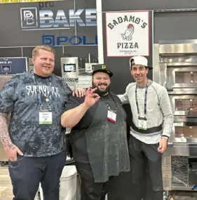  ?? ?? Anthony Badamo, center, networks with fellow pizza makers while representi­ng Polin Ovens at the Internatio­nal Pizza Expo.