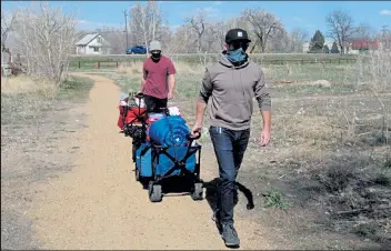  ?? MAX LEVY / Loveland Reporter-herald ?? Organizers of the Foothills Mutual Aid Collective — Colby Gergen, front, and Jaten Barney — haul carts full of gear to homeless campers in Loveland’s King’s Crossing Natural Area with U.S. 287 in the background on Sunday. The group was establishe­d last year and helps the needy in Fort Collins and Loveland by supplying meals, clothing and other essentials.