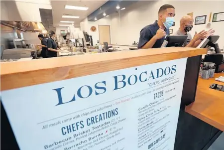  ?? AMY BETH BENNETT/SUN SENTINEL ?? Bryan Pozuelos, left, and Co-owner Anthony Hoff take lunch orders April 22 at Los Bocados in Parkland.