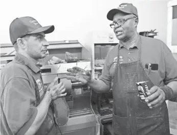  ?? LIZ DUFOUR, THE CINCINNATI ENQUIRER ?? Clarence Howell, 78, instructs Bassam Osman, 36, at Howell’s shoe repair store in Pleasant Ridge, Ohio. Osman is a Syrian refugee who came to Cincinnati with his family in July 2016.