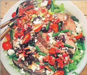  ?? ASSOCIATED PRESS PHOTO ?? A few slices of pink, perfectly cooked steak draped across a colorful bowl of Greek salad make a lunch or dinner that knows no season, but that feels particular­ly nice as the weather warms up. You can serve it up on a big platter or on individual plates.