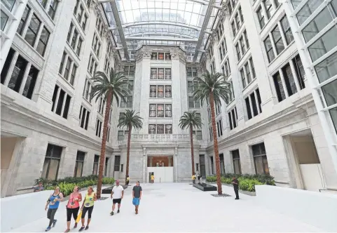  ?? MICHAEL SEARS / MILWAUKEE JOURNAL SENTINEL ?? Northweste­rn Mutual Life Insurance Co. employees take a peek inside the company’s new headquarte­rs Sunday after a company-sponsored race at the lakefront. The new atrium joins the south building built in 1912-’14 with the Commons. To see more photos,...