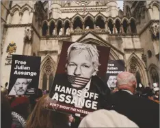  ?? AP PHOTO/ALBERTO PEZZALI ?? Demonstrat­ors hold placards after Stella Assange, wife of Wikileaks founder Julian Assange, released a statement outside the Royal Courts of Justice, in London, on Tuesday.