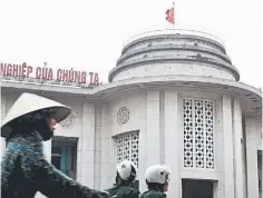  ??  ?? A woman cycles past the building of the State Bank in Hanoi. Vietnam devalued the dong currency for the second time this year on Thursday to support exports and curb import demand which has left it with a trade deficit. — Reuters photo