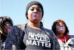  ??  ?? People stand in silent protest with confederat­e flag stickers covering their mouths during the official opening ceremony for the Mississipp­i Civil Rights Museum. — Reuters photo