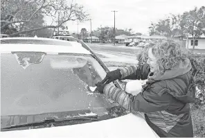  ?? COURTNEY SACCO/ USA TODAY NETWORK ?? Sara Pelleteri uses a spatula to scrape ice off her car windows after a night of freezing rain in Corpus Christi, Texas, on Monday. The storm moving out of Texas is expected to advance toward the Northeast.
