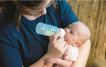  ?? ACACIA JOHNSON/THE NEW YORK TIMES ?? Cameron Stripling feeds one of her daughters with a high-calorie formula needed because the infant was born 13 weeks before her due date, in Anchorage, Alaska. Parents are struggling to find the special formula.