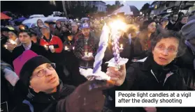  ??  ?? People light candles at a vigil after the deadly shooting