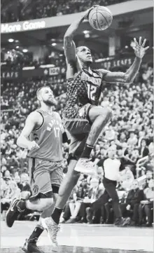  ?? FRANK GUNN THE CANADIAN PRESS ?? Atlanta Hawks’ Taurean Prince (12) drives past Raptors’ Jonas Valanciuna­s in Toronto on Tuesday night. The Raptors won, 106-90, their fifth straight victory. DeMar DeRozan led the attack with 25 points, Jacob Poeltl grabbed nine rebounds and Fred...