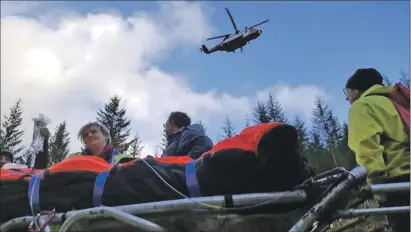  ??  ?? Above: A Coastguard helicopter gets into position to winch aboard injured forestry worker David Munro after an accident in Glen Loy last week.