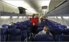  ?? CHARLIE RIEDEL — THE ASSOCIATED PRESS FILE ?? A flight attendant prepares a plane bound for Orlando, Fla., for takeoff at Kansas City Internatio­nal airport in Kansas City, Mo., last May. About 40,000workers in the airline industry are facing layoffs Thursday.