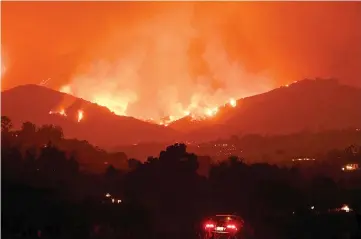  ??  ?? Nursery owner Erick Suarez sits in his car at his tree and plant nursery as he watches flames from theThomas Fire in the hills of Montecito, California. — AFP photo