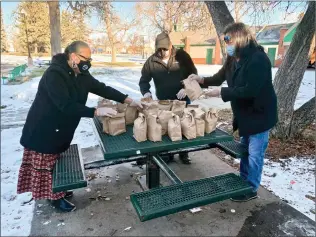  ?? Herald photo by Dale Woodard ?? Charlene Plume, at left, Roger Prairie Chicken and Robert Shade prepare lunch bags to give to the homeless Saturday afternoon at Galt Gardens.