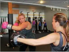  ?? MICHILEA PATTERSON — DIGITAL FIRST MEDIA ?? Christa Costello does a boxing combinatio­n with the help of her partner Megan Lewis during a boxing boot camp class at Ignite Fitness Studio in West Vincent.