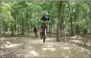  ?? NWA Democrat-Gazette/FLIP PUTTHOFF ?? Mountain bikers zip along a trail June 14 at the Lake Leatherwoo­d City Park downhill trails in Eureka Springs.