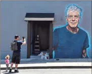  ?? Invision-Chris Pizzello) ?? Food writer Hadley Tomicki, of Los Angeles, is accompanie­d by his daughter Kira, 1, as he takes a picture of a new mural of the late chef Anthony Bourdain, created by artist Jonas Never last Monday on a side wall of the new restaurant Gramercy in Santa...