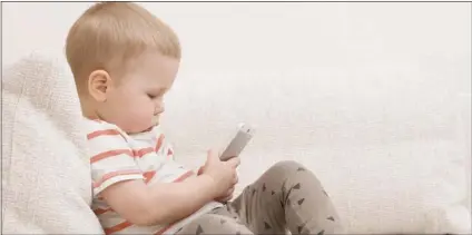  ??  ?? Adorable toddler boy sitting on the sofa in the living room and playing with smartphone. Child learning how to use smartphone. Boy texting on the phone. - TECHNOLOGY AND LIFESTYLE CONCEPT GOOD MOMENTS PHOTO / ALEXEY IVANOV