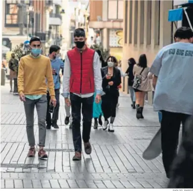  ?? RAFA DEL BARRIO ?? Dos jóvenes caminan por la calle Tres de agosto de la capital onubense durante la jornada de ayer.