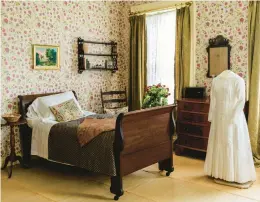  ?? ?? Emily Dickinson’s rose-wallpapere­d bedroom features a reproducti­on of one of her white dresses and her writing desk.