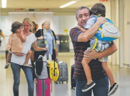  ?? Julie Jacobson, The Associated Press ?? Juan Rojas of Queens hugs 4-year-old grandson Elias as daughter-in-law Cori carries Lilly, 3, through the terminal at John F. Kennedy Internatio­nal Airport in New York on Tuesday. Cori Rojas, a teacher in Puerto Rico who fled with her children after...