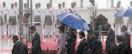  ??  ?? Discipline­d, come rain or shine: Guards standing at attention despite the rain as Yingluck and Najib arrive at Putra Square of the Prime Minister’s office yesterday.