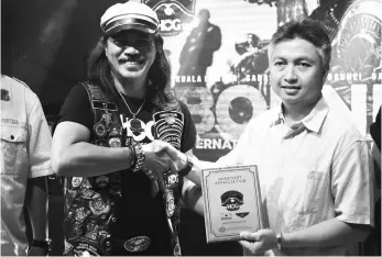  ??  ?? Snowdan (right) receives a memento from TJ Rolan during the launching ceremony of Borneo Internatio­nal Harley Owners Group (HOG) Rally Malaysia.