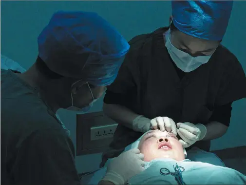  ?? PHOTOS BY JIANG DONG / CHINA DAILY ?? Bu Ren, a facial reconstruc­tion specialist at the Plastic Surgery Hospital under the Chinese Academy of Medical Sciences, conducts eyelid surgery.