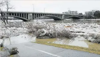  ?? JOHN RENNISON THE HAMILTON SPECTATOR ?? The Brantford waterfront trail disappears into the water near the Colborne Street bridge over the Grand River. Thousands of residents from three Brantford neighbourh­oods returned home Thursday to survey the damage.