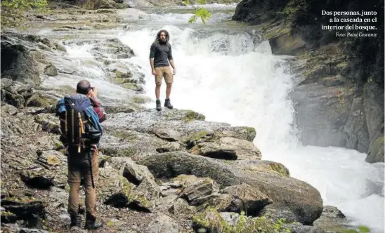  ?? Foto: Patxi Cascante ?? Dos personas, junto a la cascada en el interior del bosque.