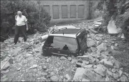  ?? INA FASSBENDER/AFP VIA GETTY IMAGES ?? A man walks past a car buried in debris after flash floods caused major damage in Hagen, western Germany, on Thursday. Heavy rains and floods lashing western Germany, Belgium, Luxembourg and the Netherland­s, causing massive damage and leaving thousands homeless. More than 100 deaths have been confirmed, and as many as 1,500 people are missing.