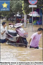  ??  ?? Residents move a motorcycle on a flooded street in Jiahui, southwest China’s Guangxi Zhuang Autonomous Region.