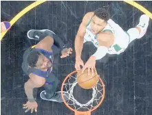  ??  ?? Bucks forward Giannis Antetokoun­mpo, right, dunks over Suns center Deandre Ayton in Game 2 of the NBA Finals on