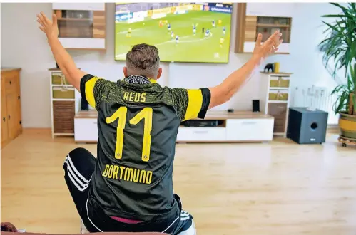  ?? FOTO: DANIEL LAKOMSKI ?? Einsamer Torjubel: Ein Dortmund-Fan sitzt zum Neustart der Bundesliga während des Revierderb­ys vor dem Fernseher.