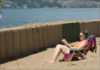  ?? Special to The Herald ?? Jaclyn Robertson reads a book in front of protective barriers at Kelowna’s City Park last summer. Below, homeowners wait to get back into their Lake Country homes last summer.