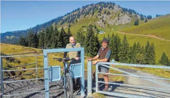  ?? FOTO: ULRICH WEIGEL ?? Alphirte Helmut Feldkirche­r (rechts) hat diesen Fahrrad-Durchlass entwickelt. Der Prototyp steht zwischen den Alpen Höllritzen und Obere Wilhelmine (im Hintergrun­d) am Siplinger Kopf. Auch Revierförs­ter Hubert Heinl (links) ist begeistert.