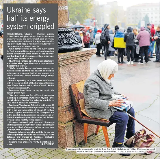  ?? Picture: REUTERS ?? A woman sits as people wait in line for food distributi­on after Russia’s retreat
from Kherson, Ukraine, November 17, 2022.