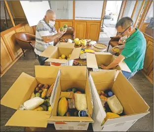  ??  ?? Workers pack boxes that The Harvest: Amazonian Barter will deliver to people who subscribe to the service.