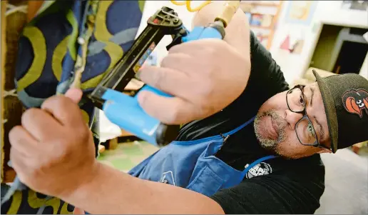  ?? TIM COOK/THE DAY ?? Jonathan Holland, owner of K&amp;J Upholstery in Groton, works on reupholste­ring a wingback chair at the workshop last week.